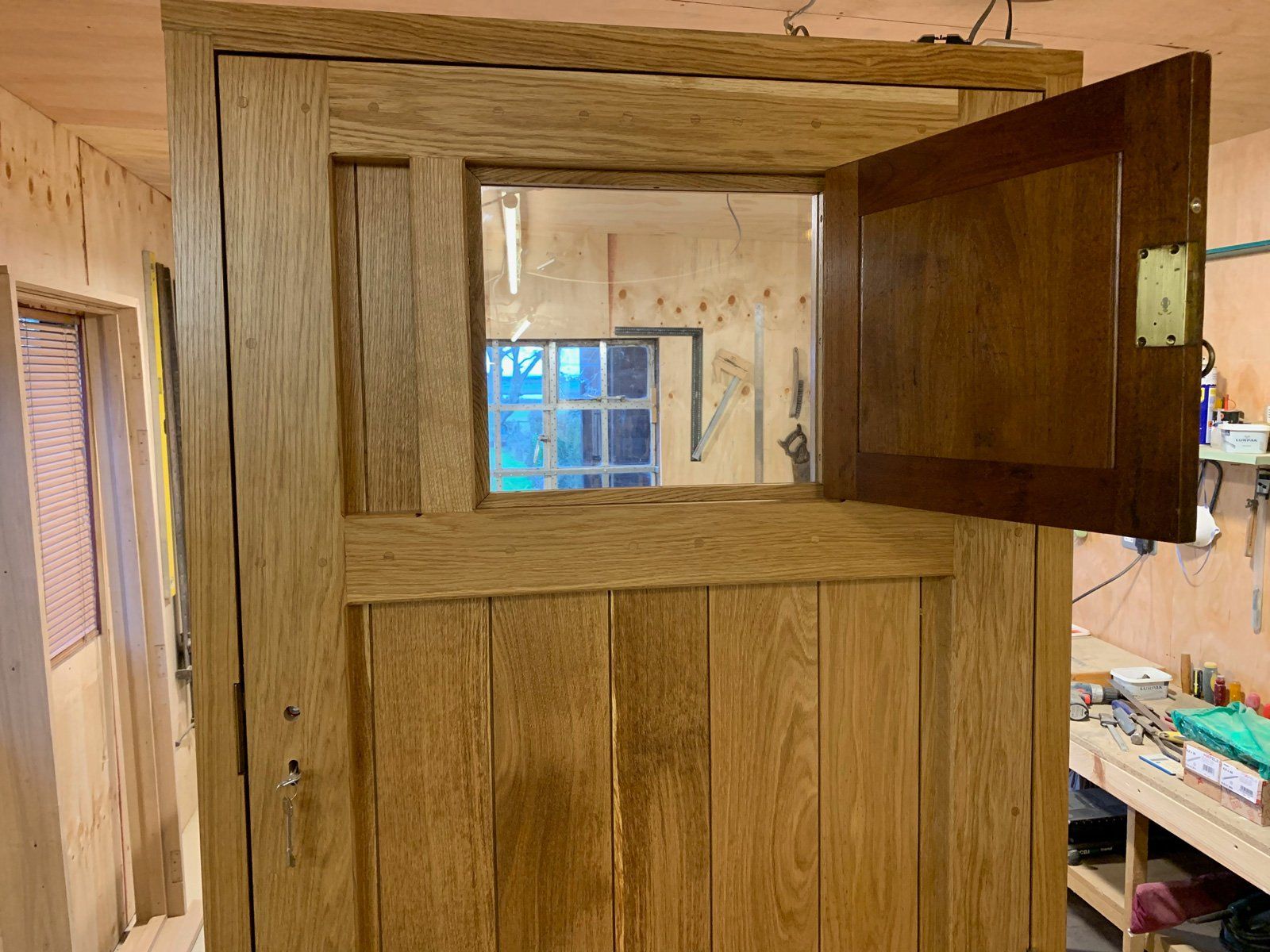 A wooden door with the door open and a window in a room.
