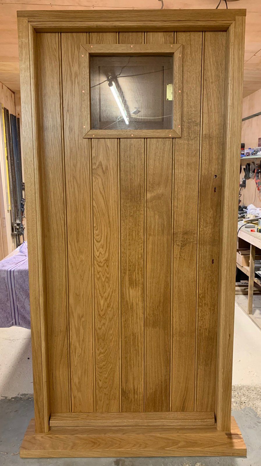 A wooden door with a small window in a room.