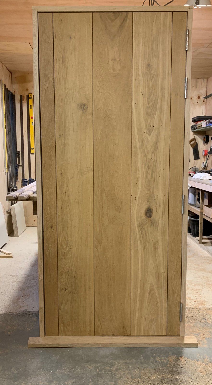 A wooden door is sitting in a woodworking shop.