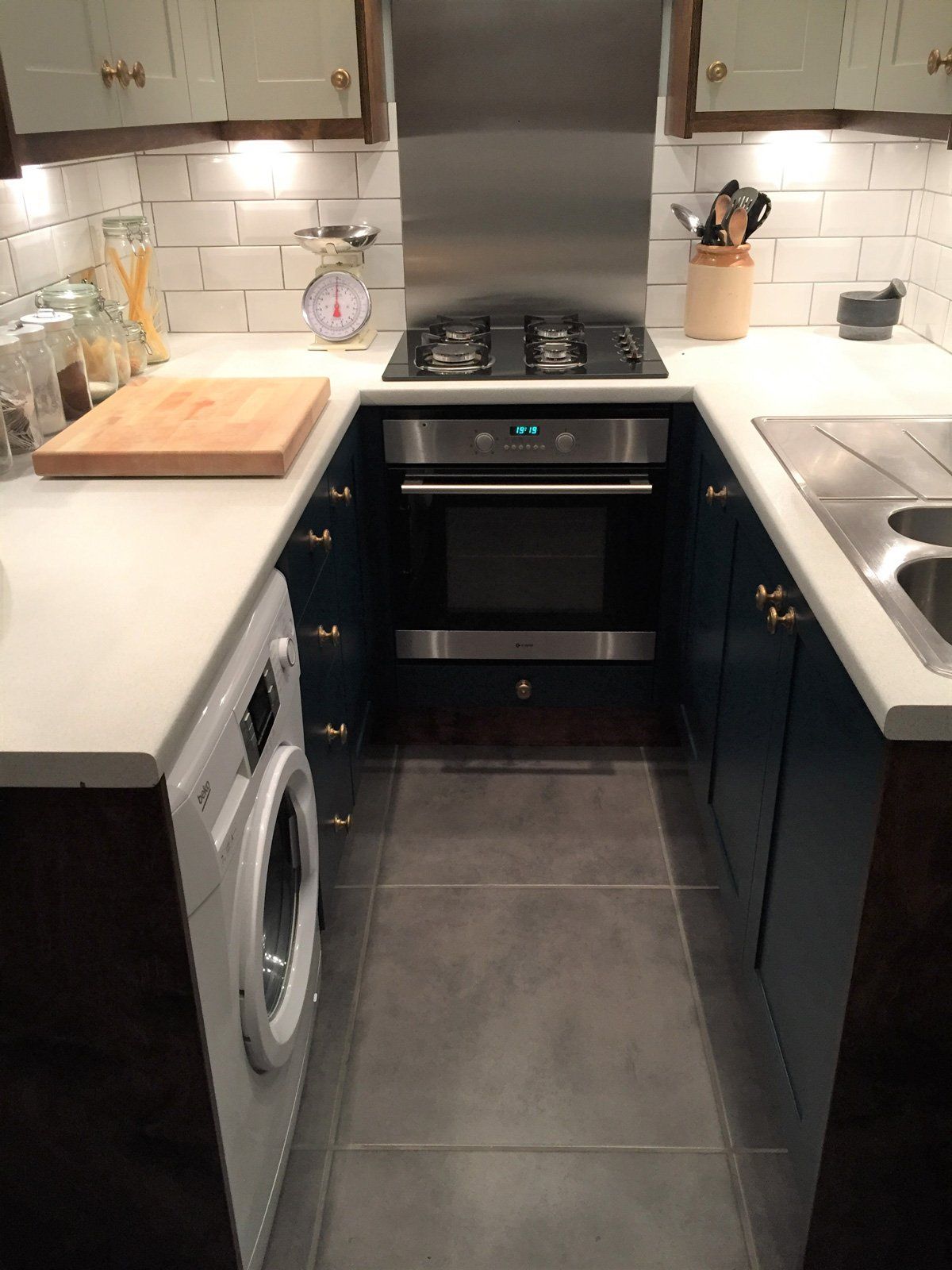 A kitchen with a stove , sink , washer and dryer