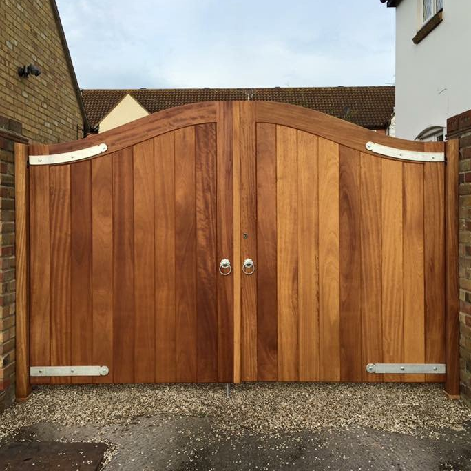 A wooden gate is sitting in front of a brick wall.