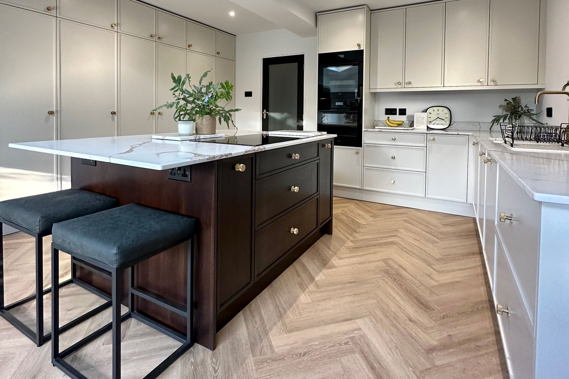 A kitchen with a large island in the middle and two stools.