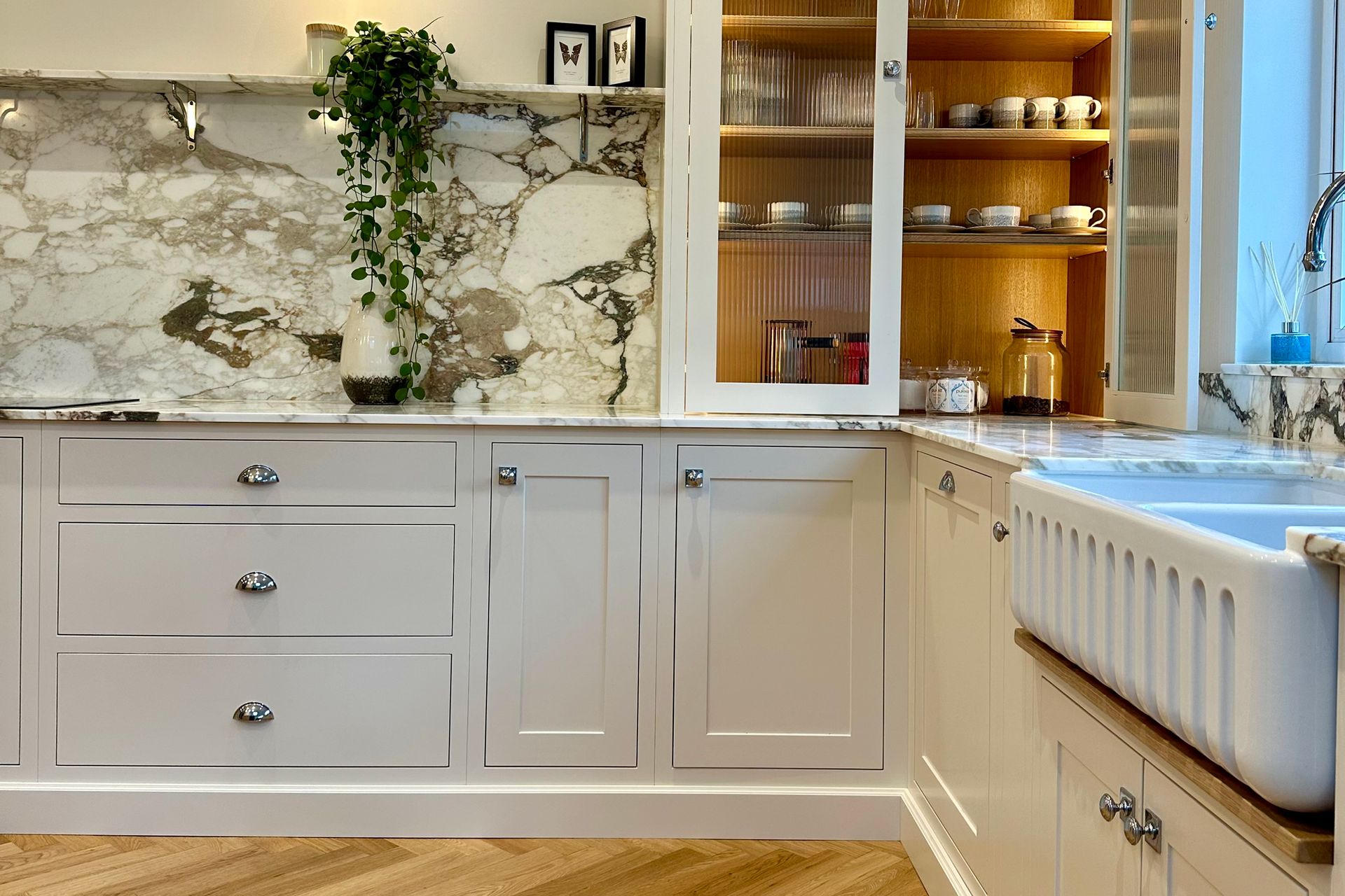 A kitchen with white cabinets, a sink, and a marble countertop.