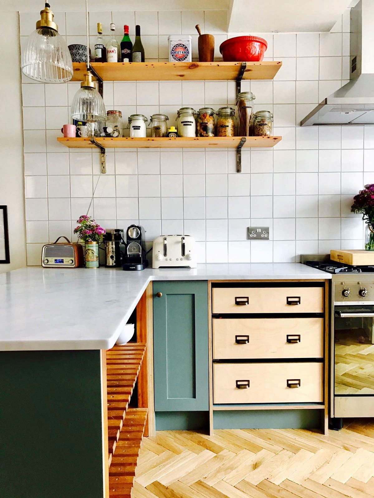 A kitchen with wooden shelves and drawers and a stove