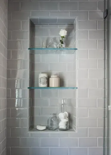 There is a shelf in the shower with glass shelves.