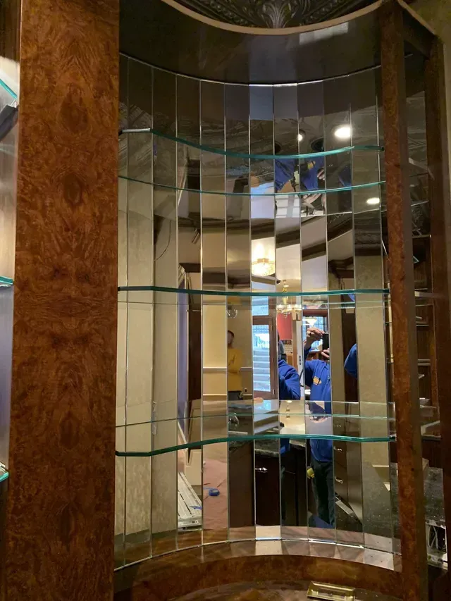 A shelf filled with lots of clear glass bottles and glasses.