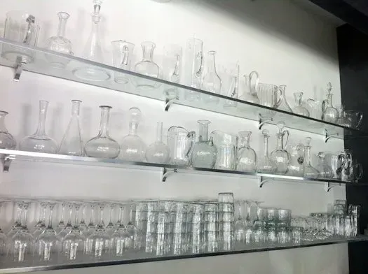 A shelf filled with lots of clear glass bottles and glasses.