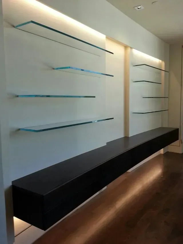 A long shelf with glass shelves hanging on a wall