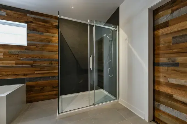 A bathroom with a walk in shower and a wooden wall.
