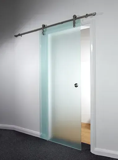 A sliding glass door is hanging on a white wall in a hallway.