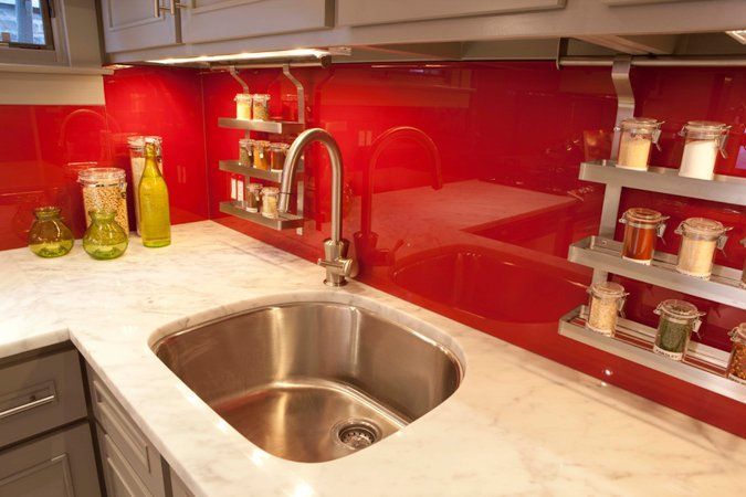 A kitchen with a stainless steel sink and a red wall