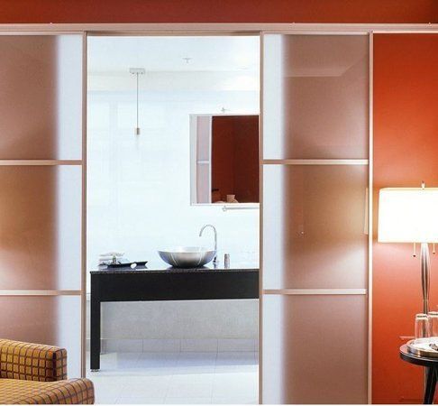 A sliding glass door leads to a bathroom with a sink