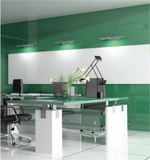 A modern office with green walls and a glass desk