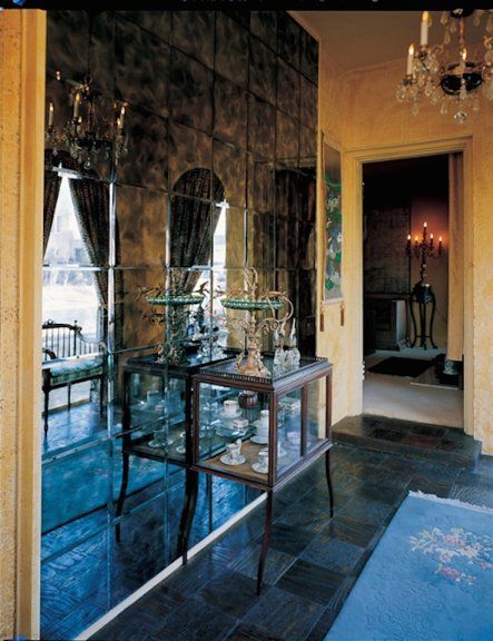A hallway with a mirrored wall and a glass display case