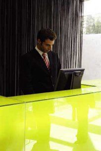 A man in a suit and tie is standing at a counter with a computer.