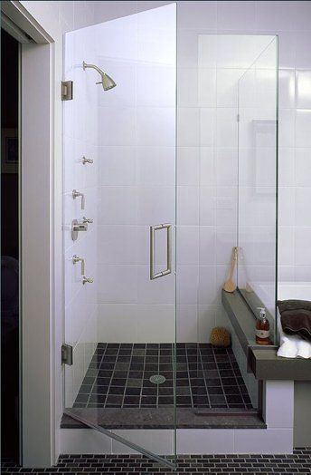 A bathroom with a walk in shower with a glass door