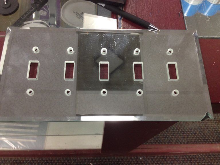 A light switch cover is sitting on a table next to a pen