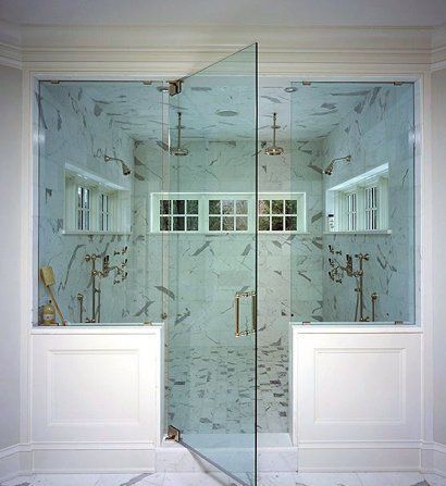A bathroom with a walk in shower with a glass door