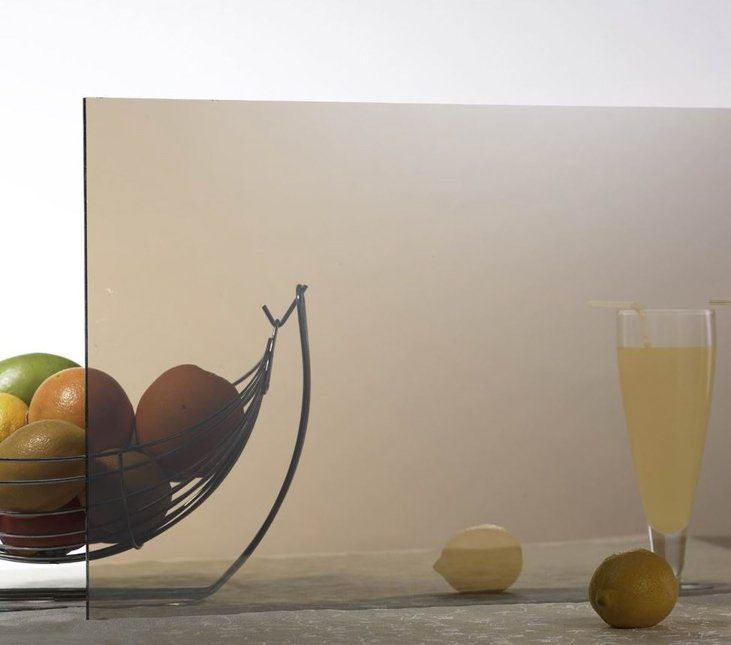 A glass of juice sits next to a fruit basket on a table.