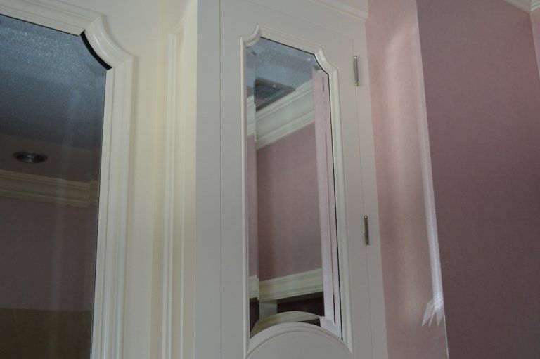 A white door with a mirror on it in a room with pink walls.