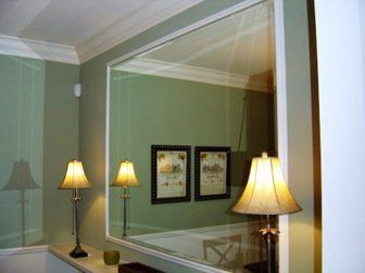 A large mirror is hanging on a wall next to two lamps.