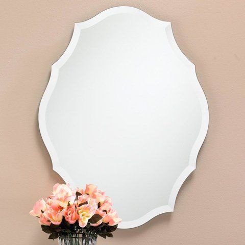 A white mirror with a vase of pink flowers in front of it
