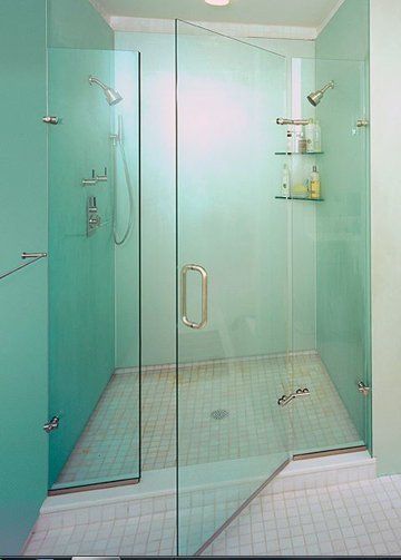 A bathroom with a walk in shower with a glass door