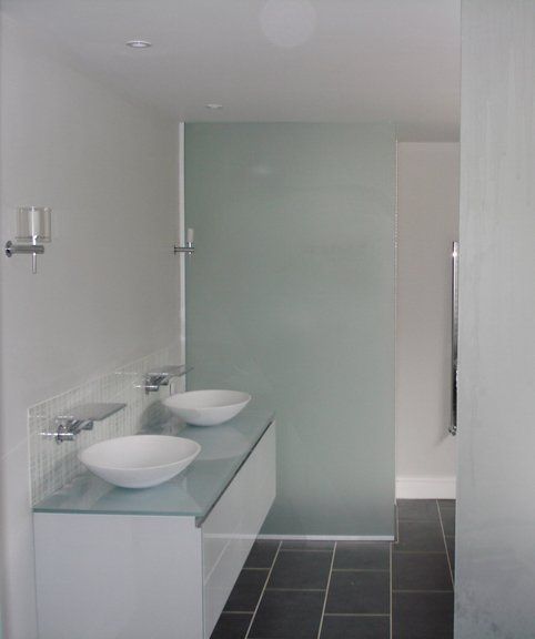 A bathroom with two sinks and a glass wall