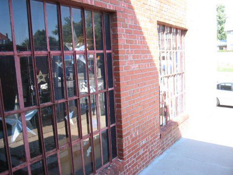 A brick building with a lot of windows and a white car parked in front of it.