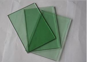 Three pieces of green glass are stacked on top of each other on a table.
