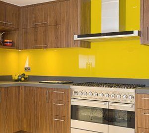 A kitchen with yellow walls , wooden cabinets , a stove , and a hood.