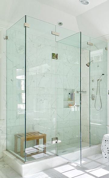 A bathroom with a walk in shower with a glass door