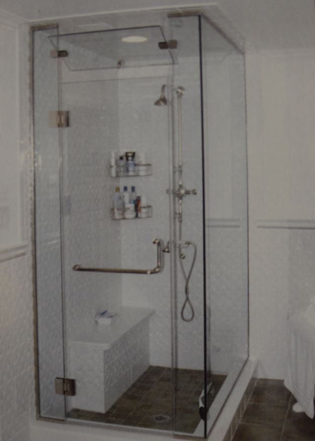 A bathroom with a walk in shower with a glass door