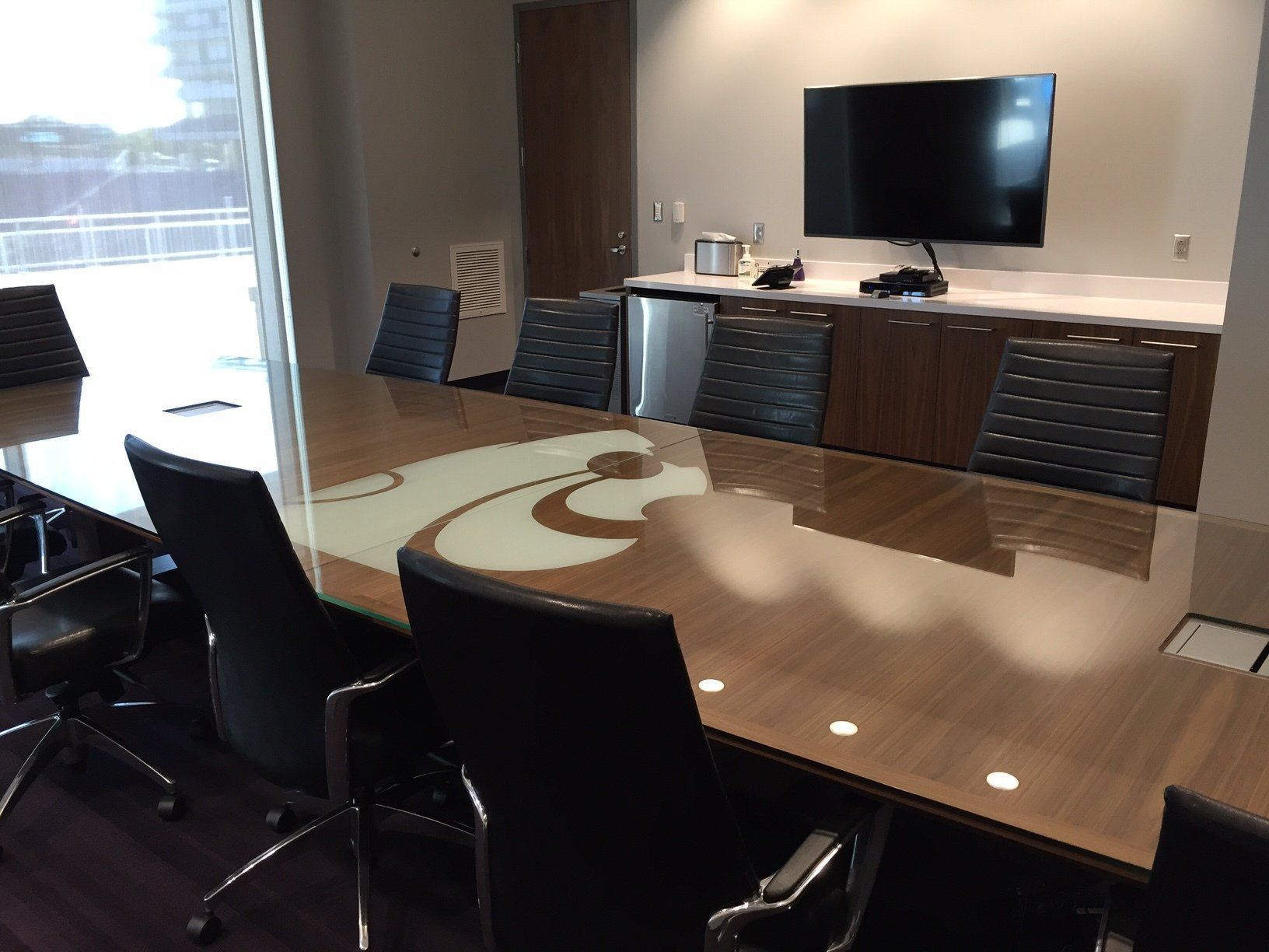A conference room with a table and chairs and a tv