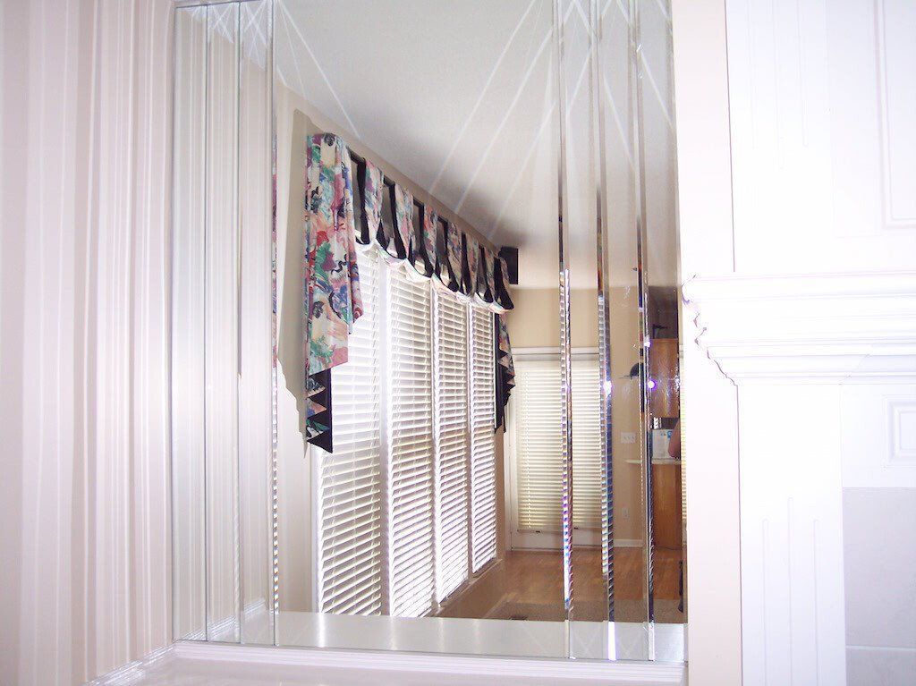 A large mirror is hanging on a wall in a room.