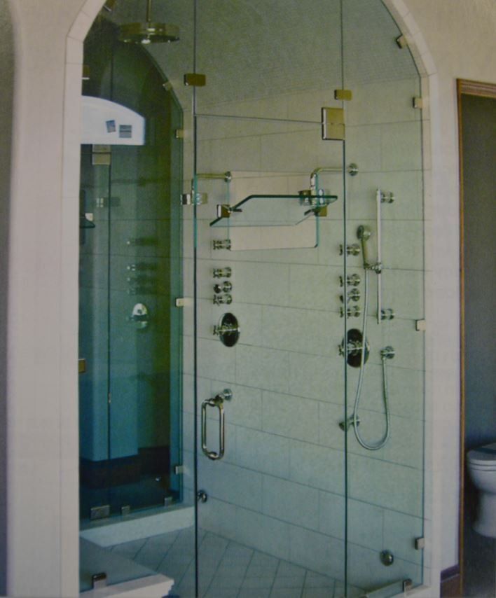 A bathroom with a walk in shower with a glass door