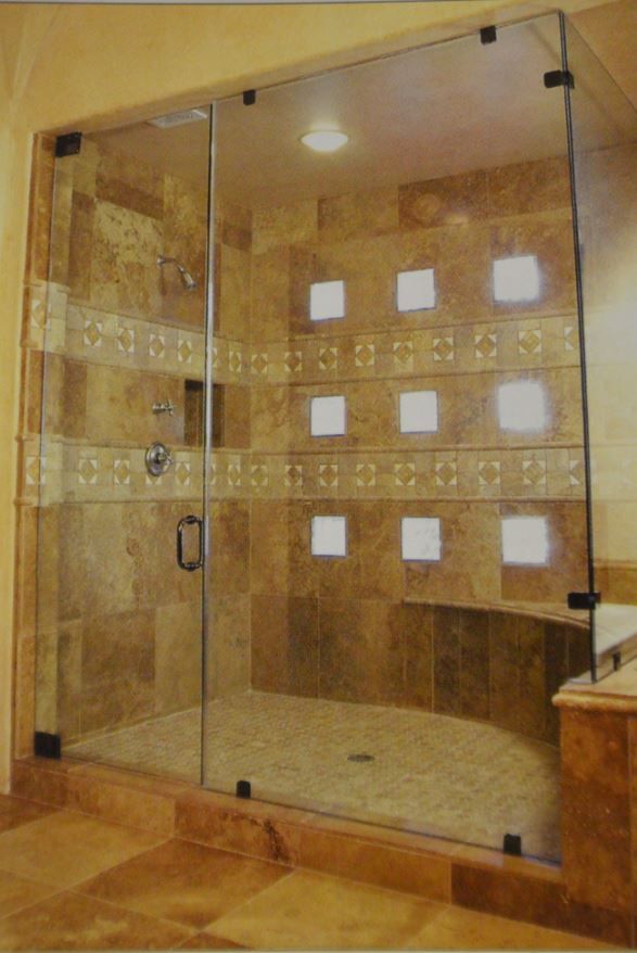 A bathroom with a walk in shower with a glass door