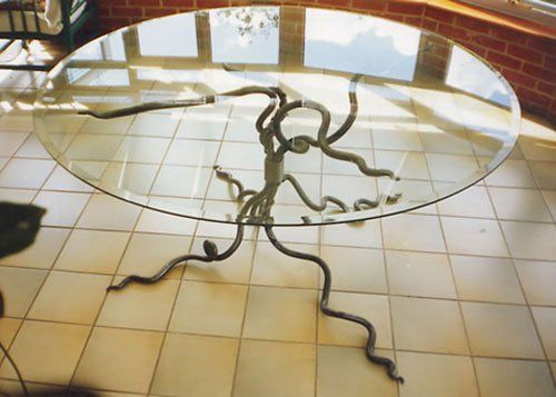 A round glass table with a wrought iron base