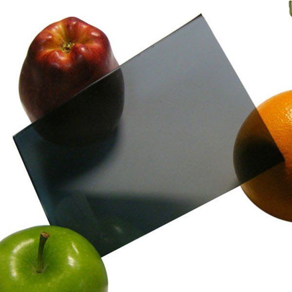 Two apples and an orange are next to a piece of glass