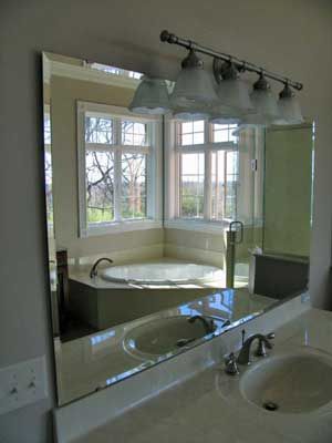 A bathroom with two sinks , a tub , and a large mirror.