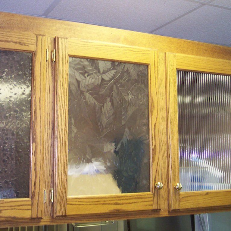 A cat is behind a glass door in a cabinet
