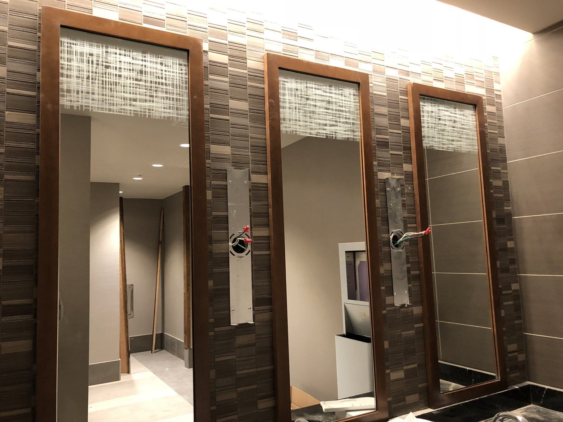 A bathroom with three mirrors on the wall and a sink