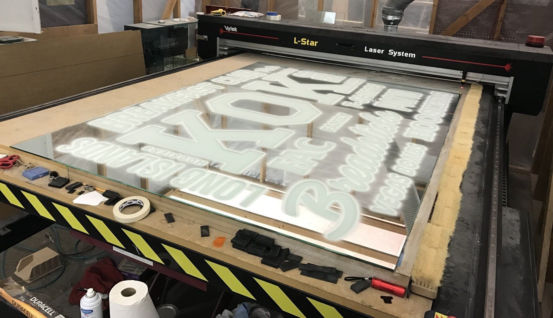 A large piece of acrylic is being cut on a machine.