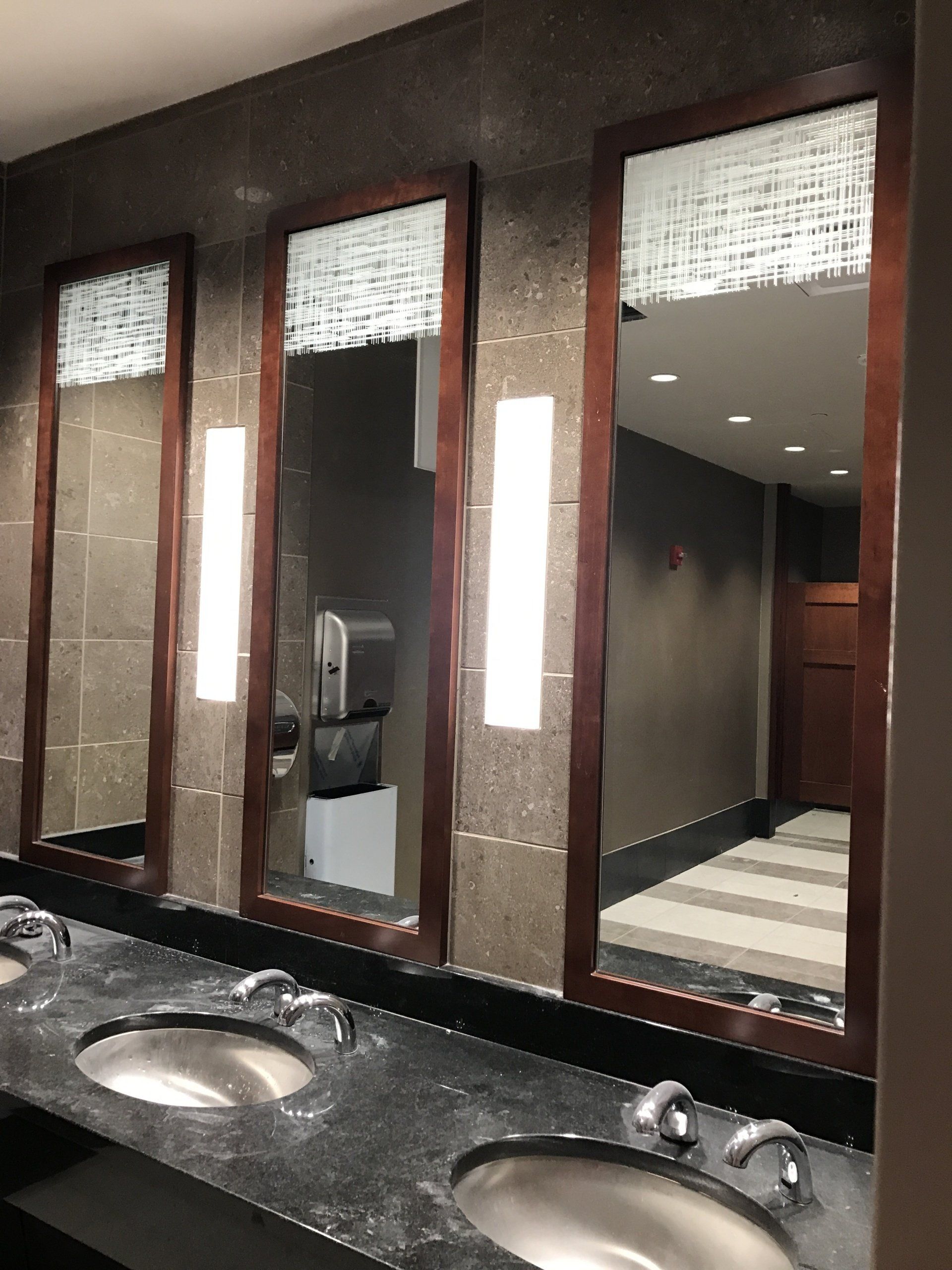 A bathroom with three sinks and three mirrors
