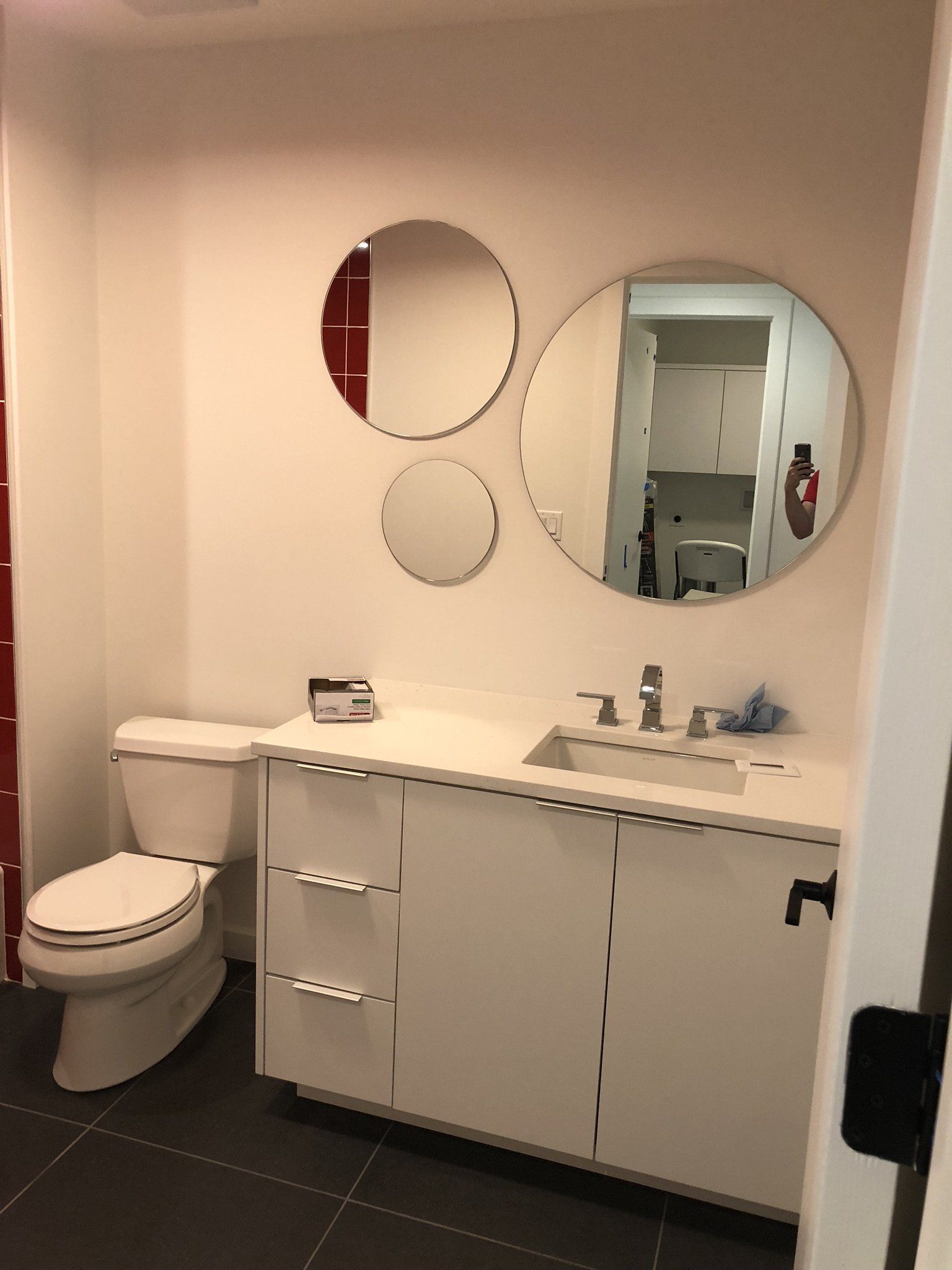 A bathroom with a toilet a sink and three mirrors