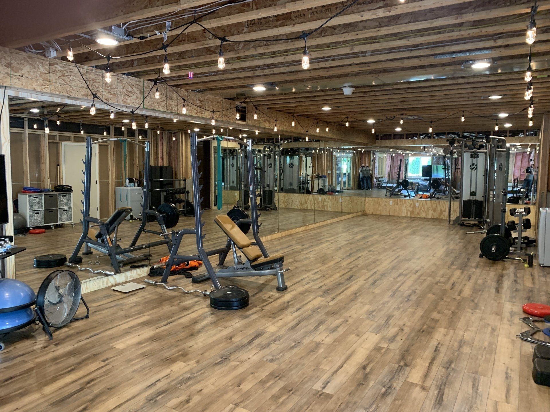 A large gym filled with lots of exercise equipment and mirrors.