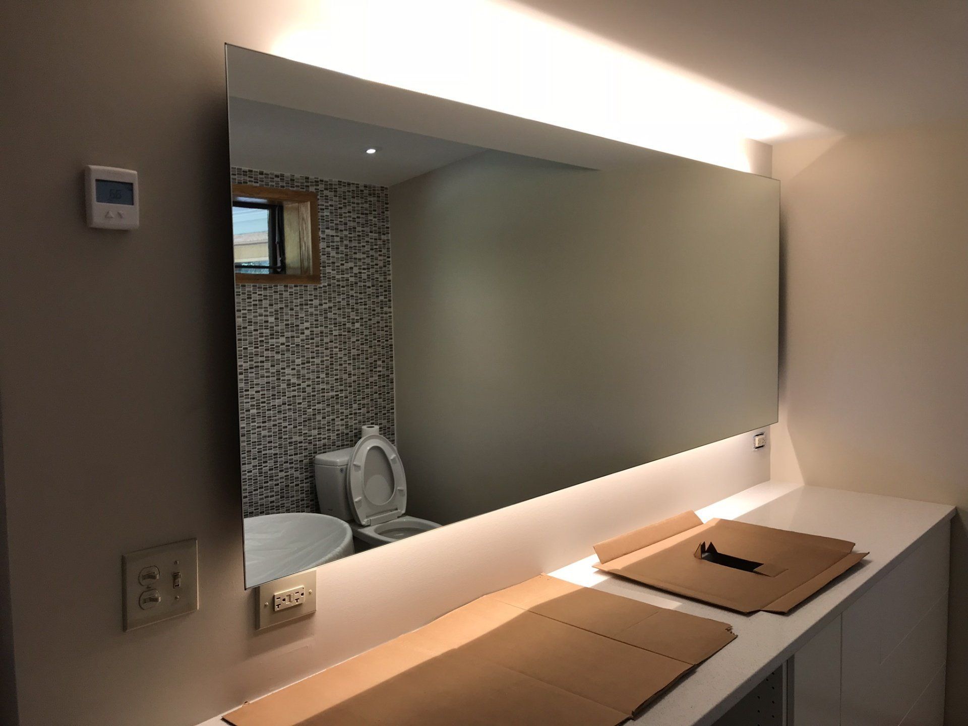 A bathroom with a toilet , sink and mirror.