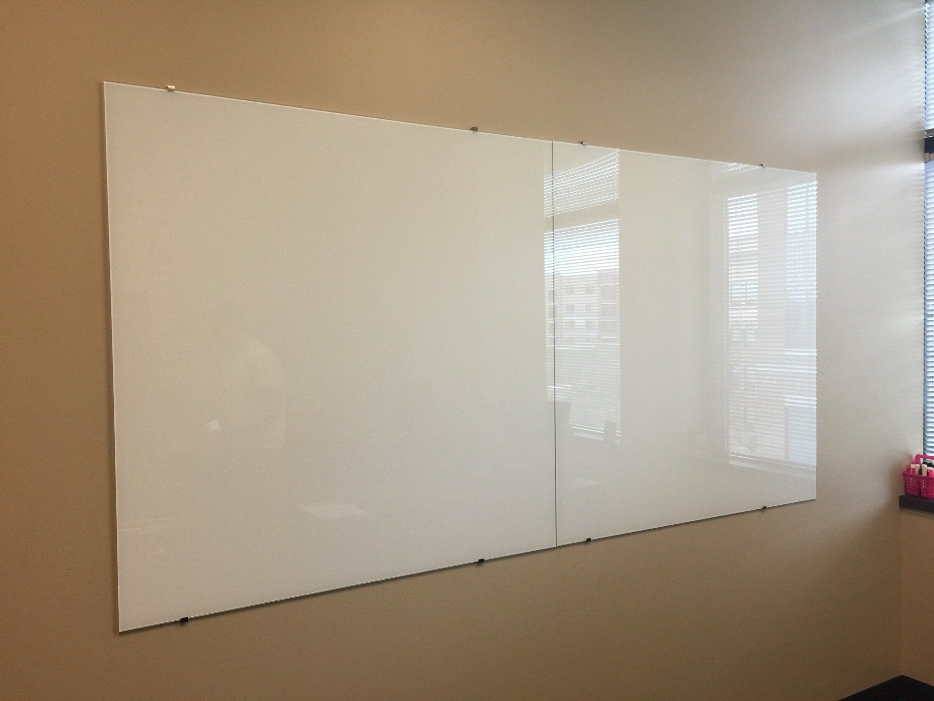 A large whiteboard is hanging on a wall next to a window.