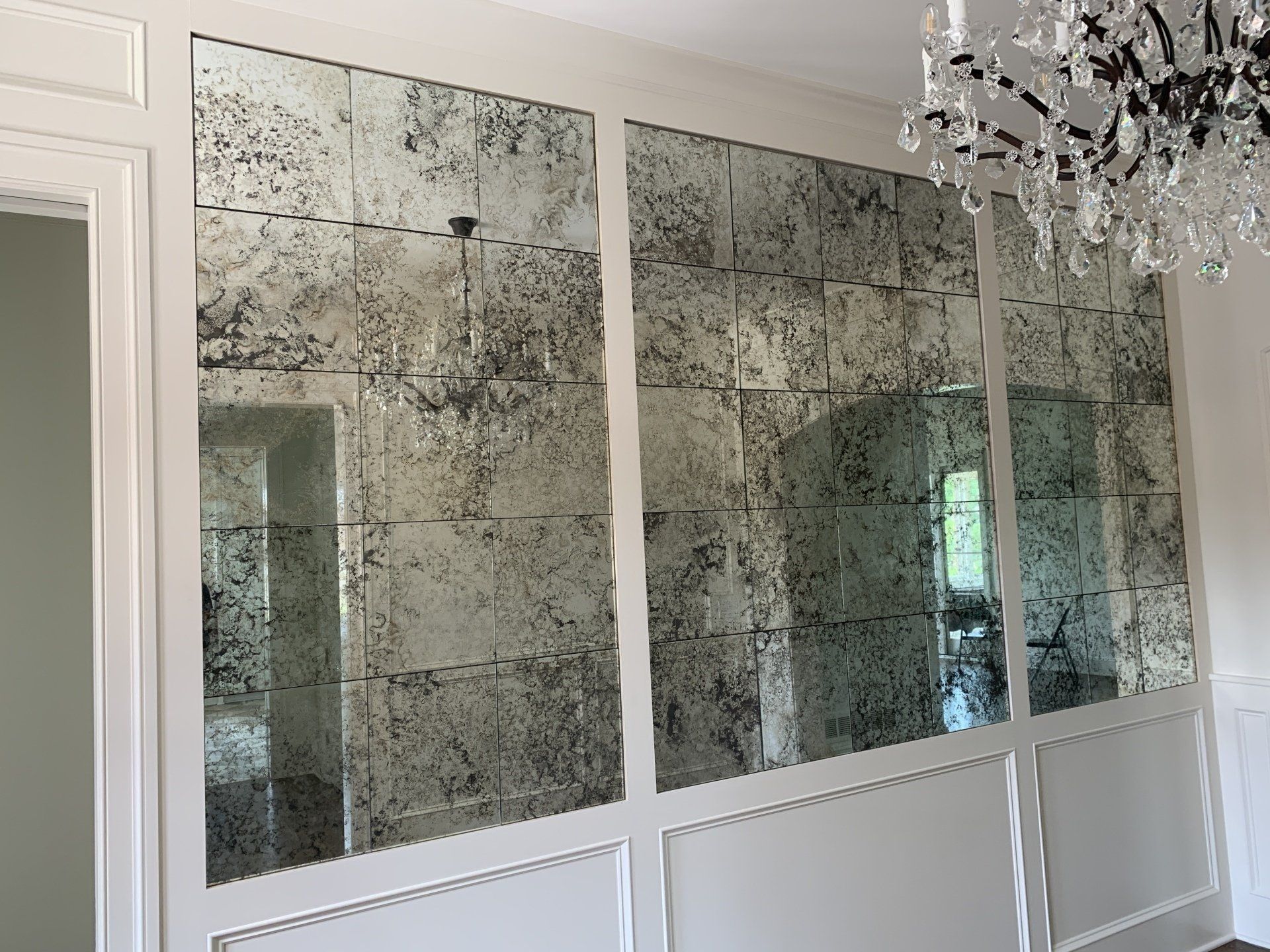 A room with a lot of mirrors on the wall and a chandelier hanging from the ceiling.