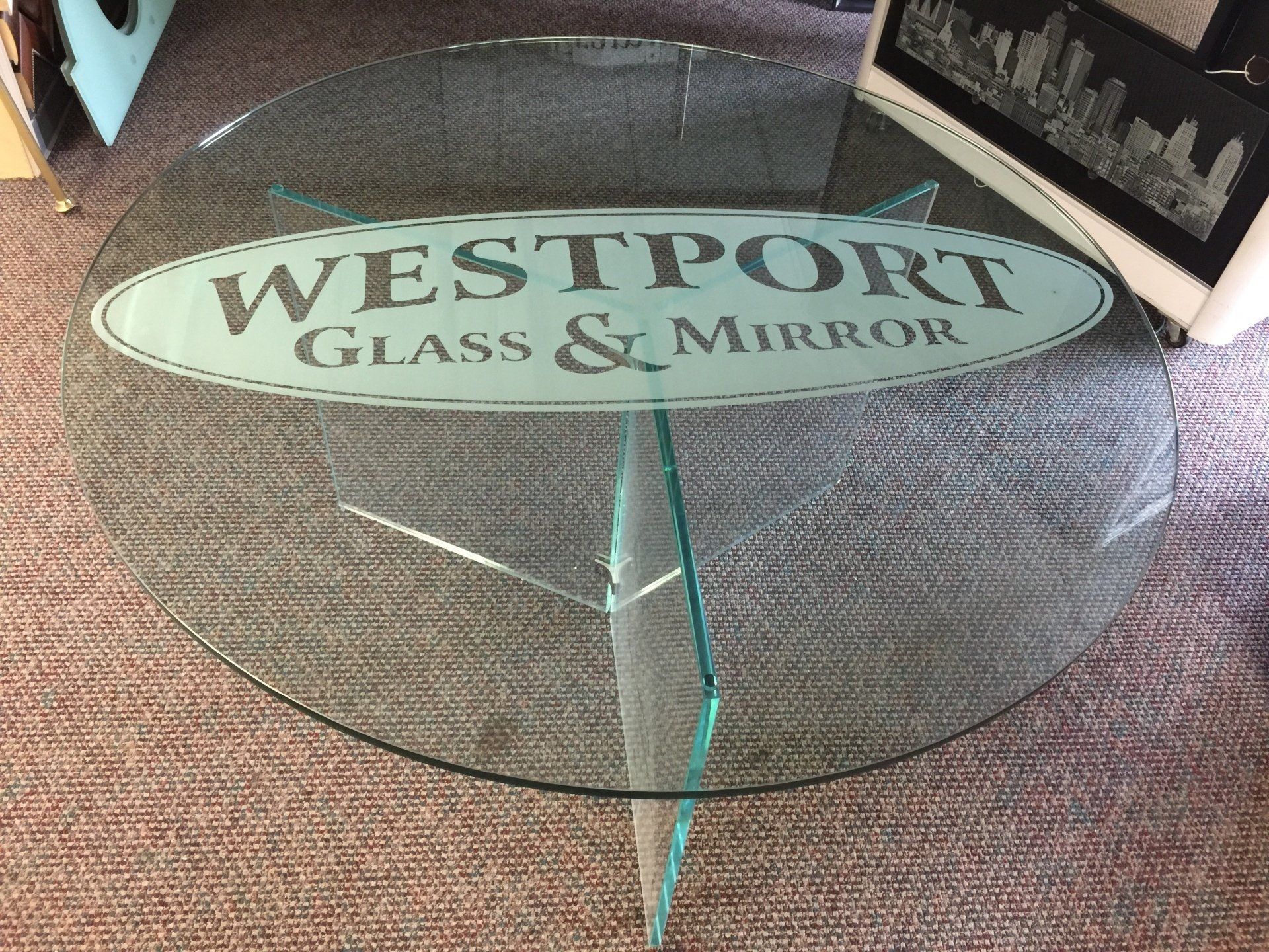 A round glass table with a westport glass and mirror logo on it